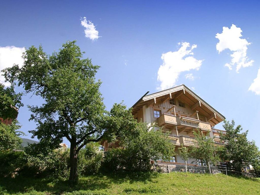 Bauernhof Kreidl in idyllischer Lage, umgeben von Bäumen und den Alpen im Hintergrund.